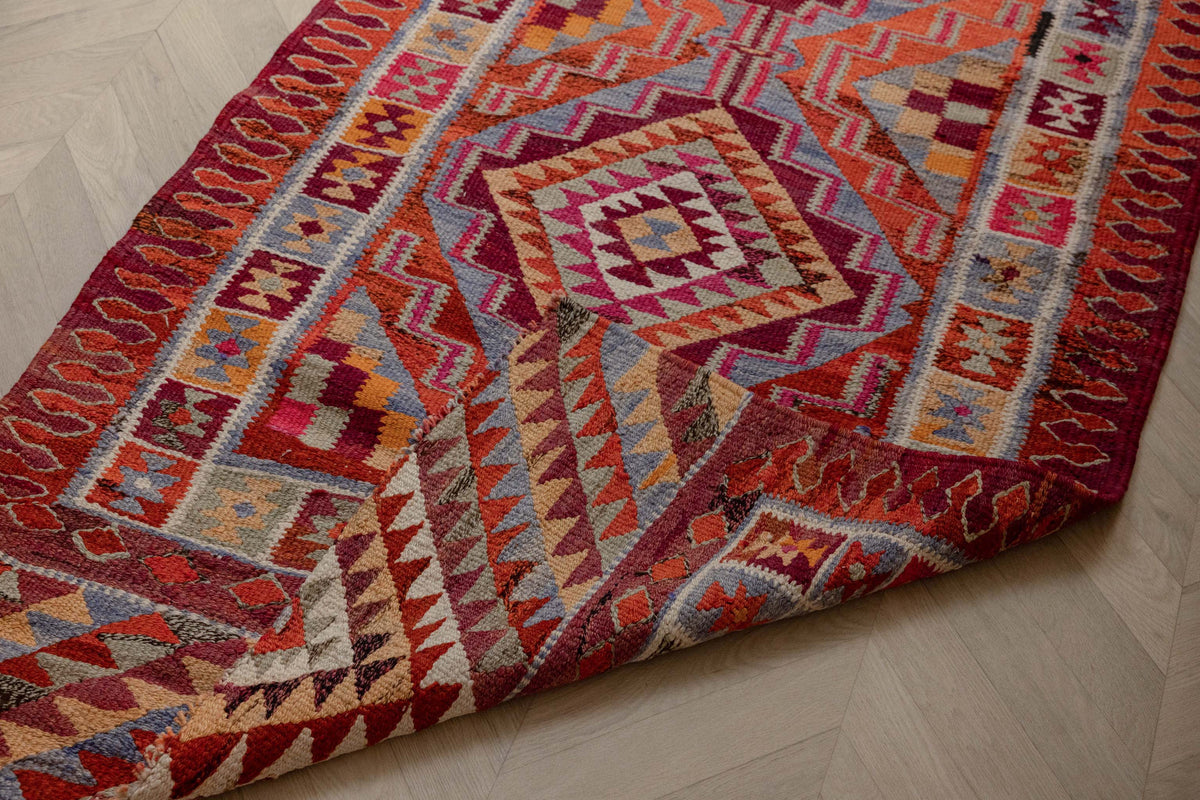 Handmade 3.4x11.3 ft wool and cotton kilim runner with orange and pink geometric maximalist patterns.