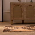 Hand-woven 2x4 ft vintage Turkish wool rug with orange and brown geometric patterns on a wooden floor.