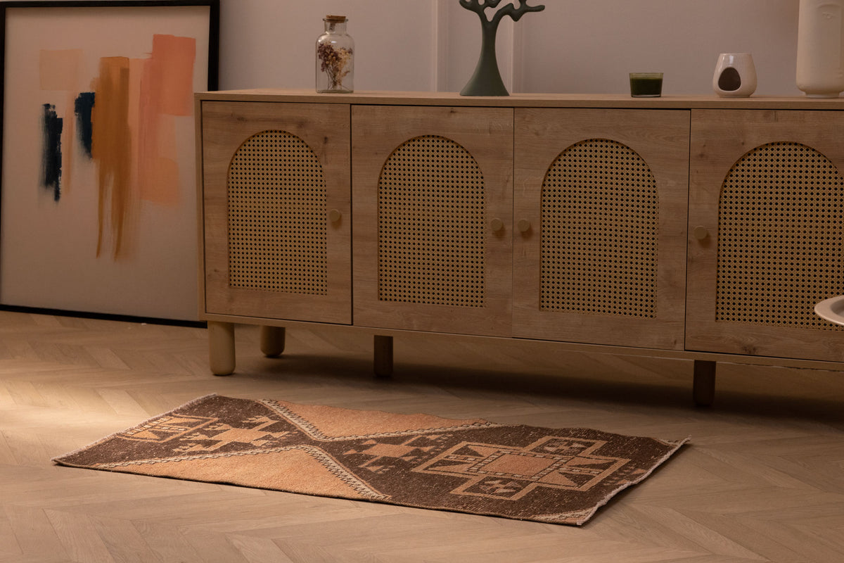 Vintage 2x4 ft Turkish wool and cotton doormat with orange and brown geometric patterns on a wooden floor.