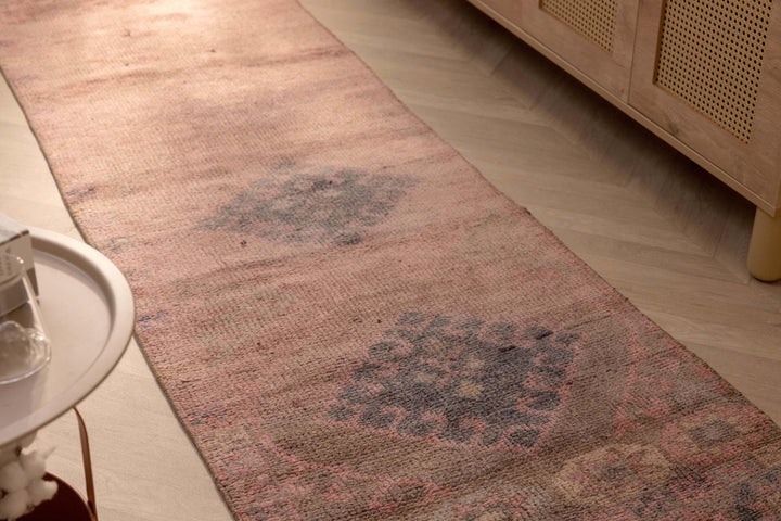 Handmade 2.7x9.5 ft wool and cotton runner rug in bohemian pink and brown with geometric patterns on a wooden floor.
