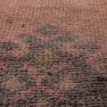 Close-up of a handmade wool and cotton Persian-style runner rug featuring a bohemian geometric pattern in brown and pink.