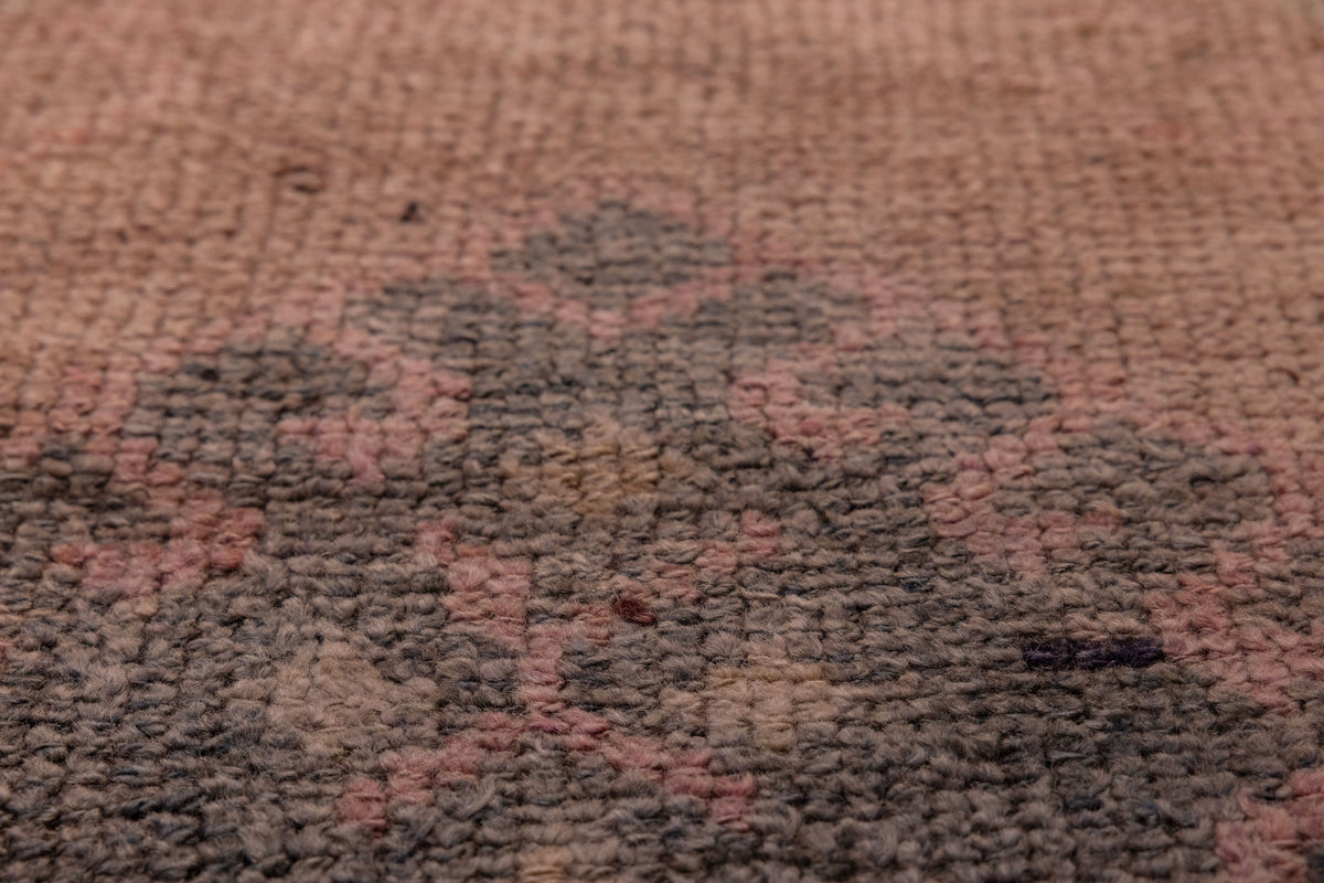 Close-up of a handmade wool and cotton Persian-style runner rug featuring a bohemian geometric pattern in brown and pink.
