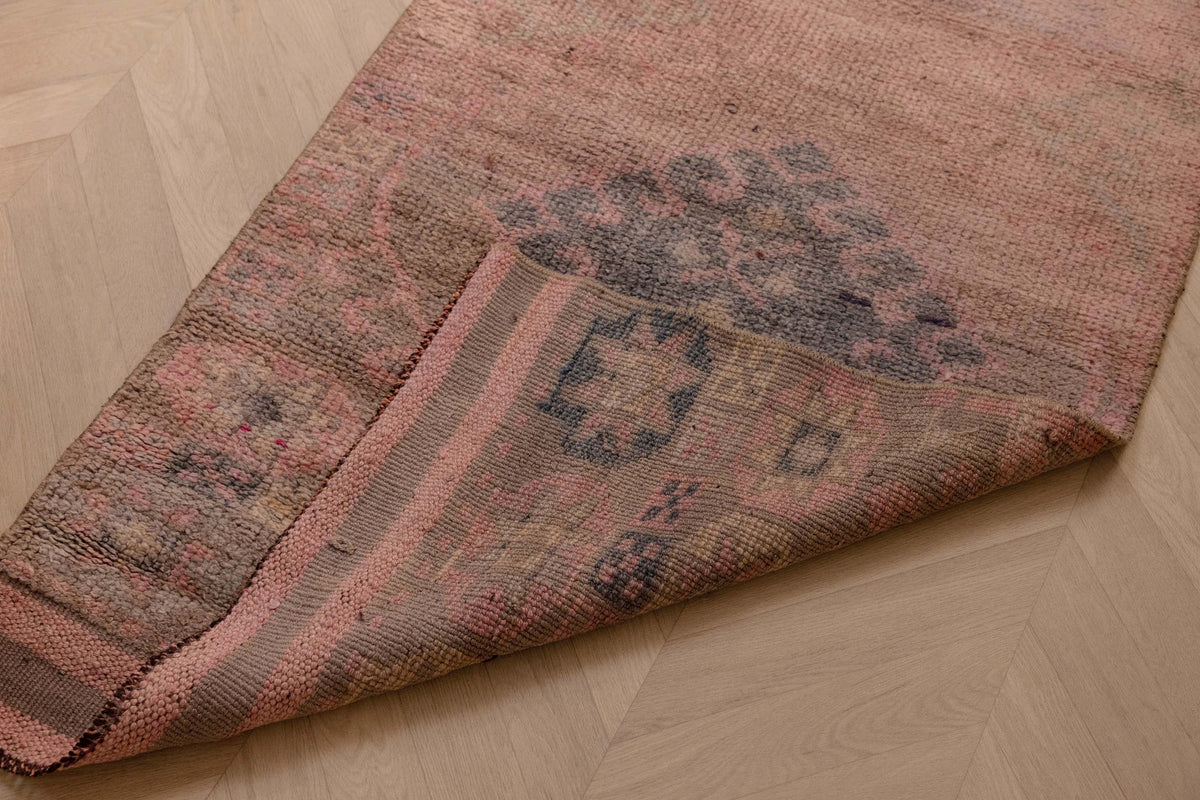 Handmade 2.7x9.5 ft wool and cotton Persian-style runner rug in pink and brown with bohemian geometric patterns.