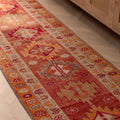 Handmade 13.5ft wool and cotton runner rug in red and orange with a bohemian floral pattern.