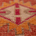 Close-up of a handmade wool and cotton runner rug featuring vibrant red and orange bohemian floral patterns.