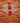 Close-up of a handmade wool and cotton runner rug featuring vibrant red and orange bohemian floral patterns.