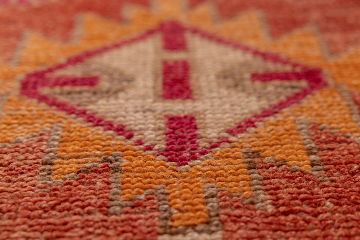 Close-up of a handmade wool and cotton runner rug featuring vibrant red and orange bohemian floral patterns.