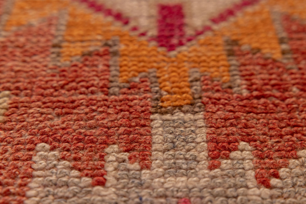 Close-up of a handmade wool and cotton Persian-style runner rug with red, orange, and beige floral patterns.