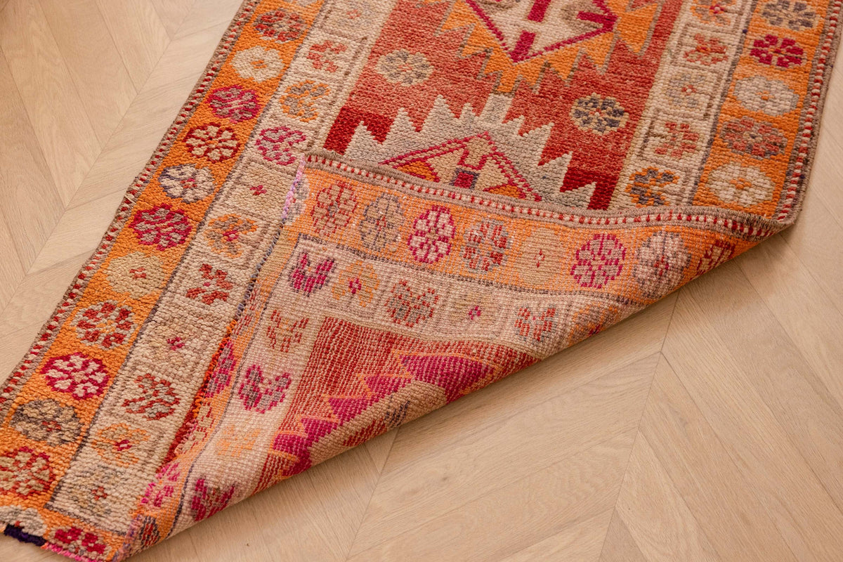 Handmade 2.6 x 13.5 ft wool and cotton Persian-style runner rug in red and orange with maximalist floral patterns.