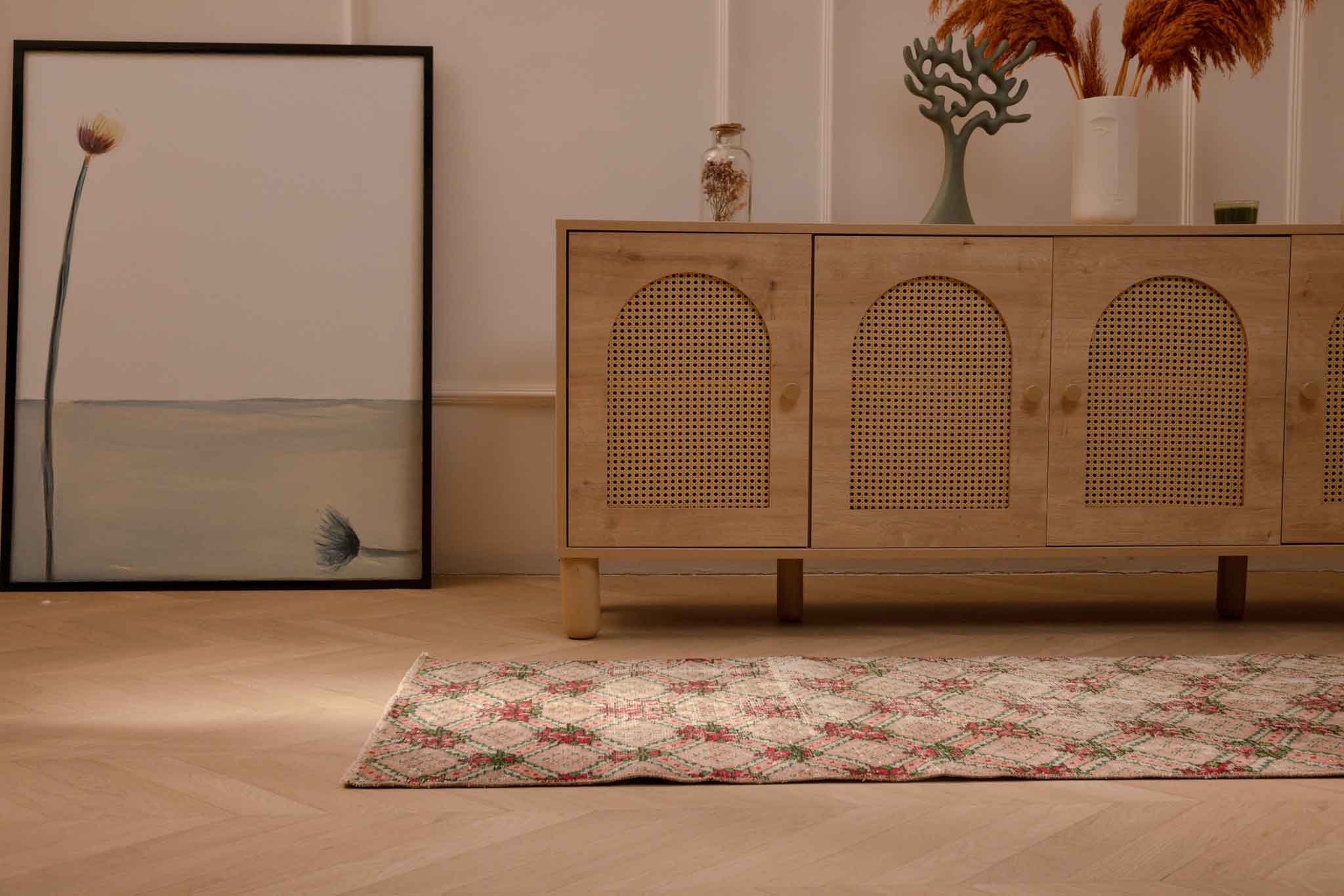 Vintage beige Turkish runner rug with distressed pink floral patterns in a bohemian living room setting.