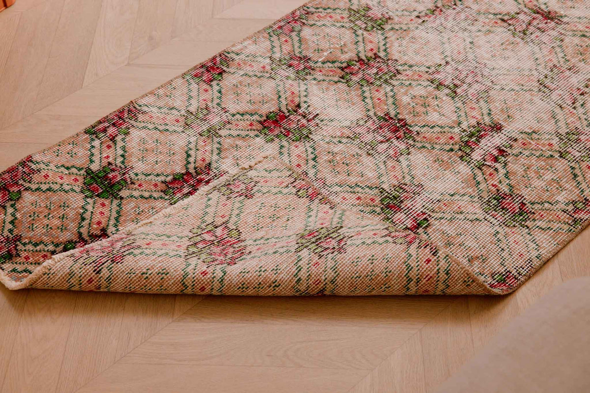 Vintage beige and pink floral Turkish runner rug, hand-woven wool and cotton with a distressed bohemian design.