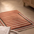 Handmade 2x3 ft vintage Turkish Isparta rug with red and beige stripes on a wooden herringbone floor.