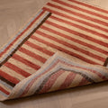 Hand-woven 2x3 ft vintage Isparta wool and cotton rug with red and beige stripes on a herringbone wood floor.