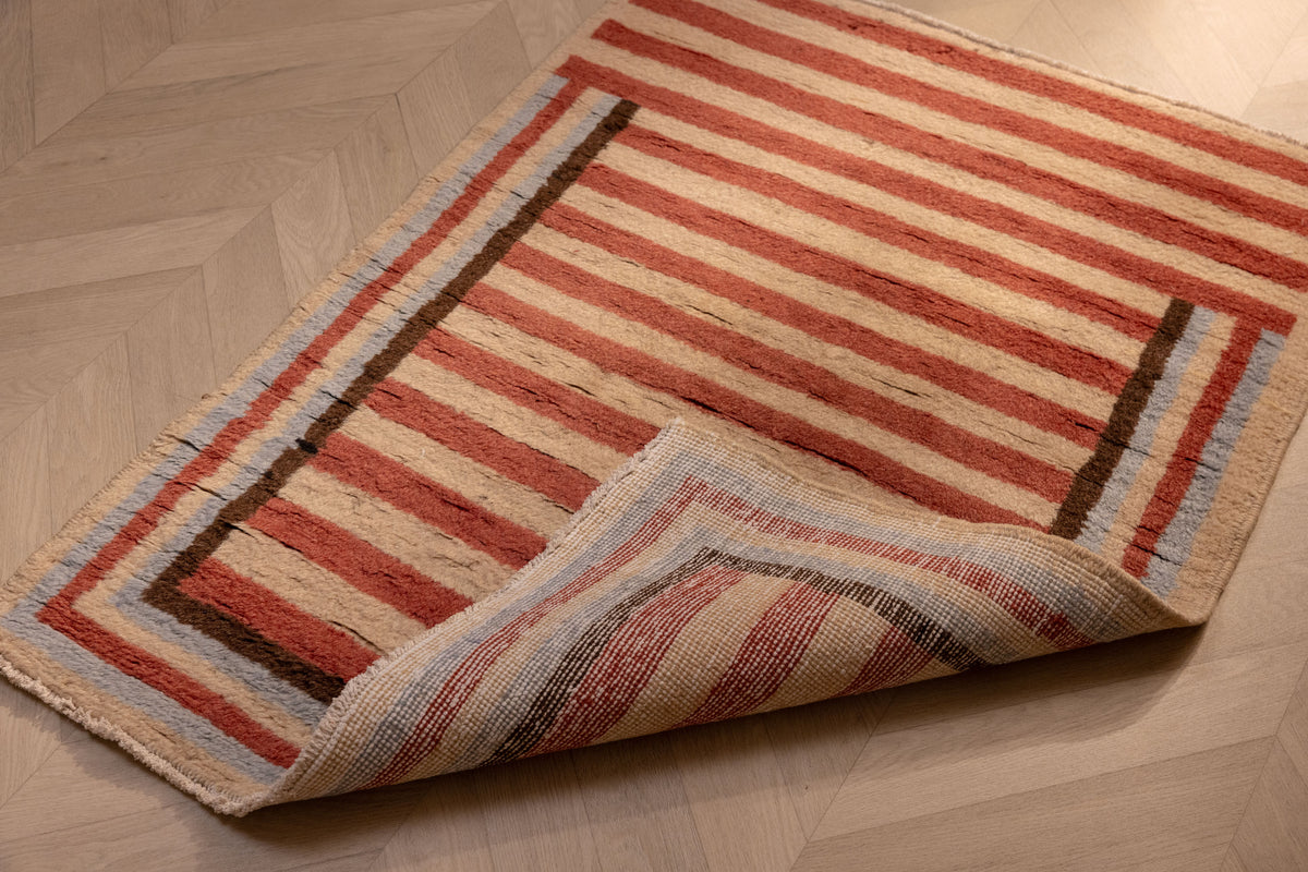 Hand-woven 2x3 ft vintage Isparta wool and cotton rug with red and beige stripes on a herringbone wood floor.