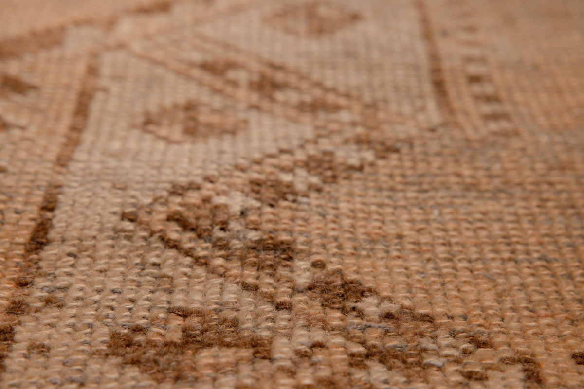 Close-up of a vintage hand-woven Turkish runner rug in beige and brown with a distressed geometric wool-cotton weave.