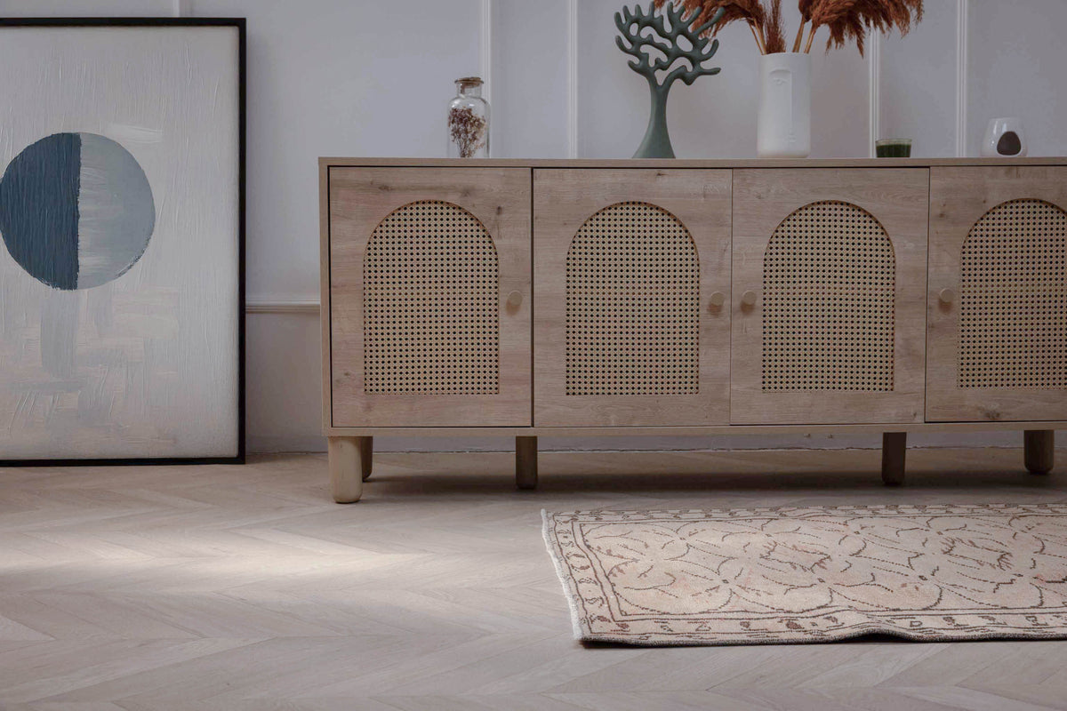 Hand-woven beige vintage Turkish area rug with distressed minimalist patterns on a light herringbone wood floor.