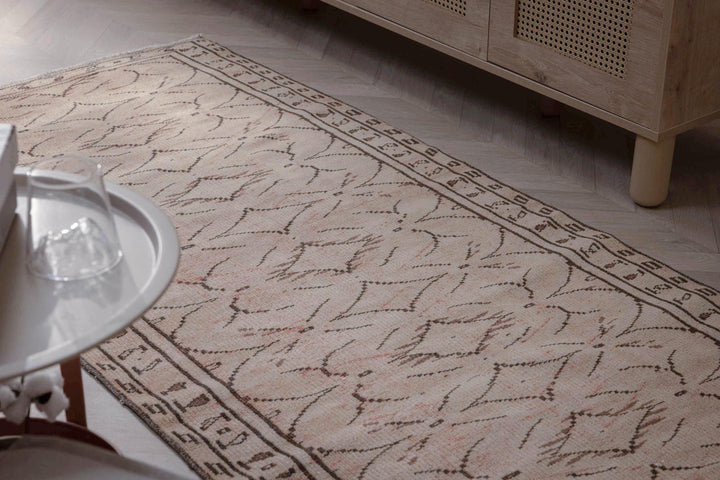 Hand-woven beige vintage Turkish area rug with a distressed minimalist pattern, crafted from wool and cotton.
