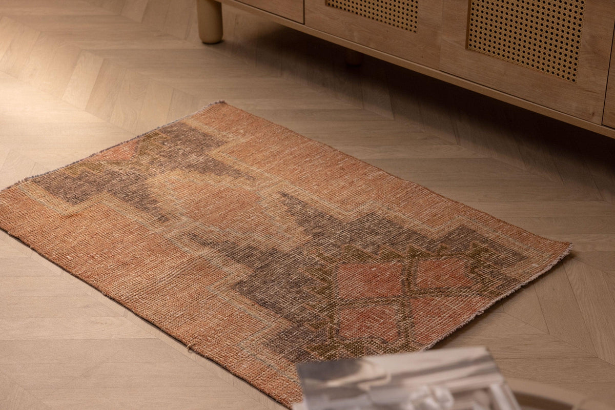 Hand-woven vintage Turkish doormat in brown and gray wool-cotton blend with geometric patterns on a wooden floor.