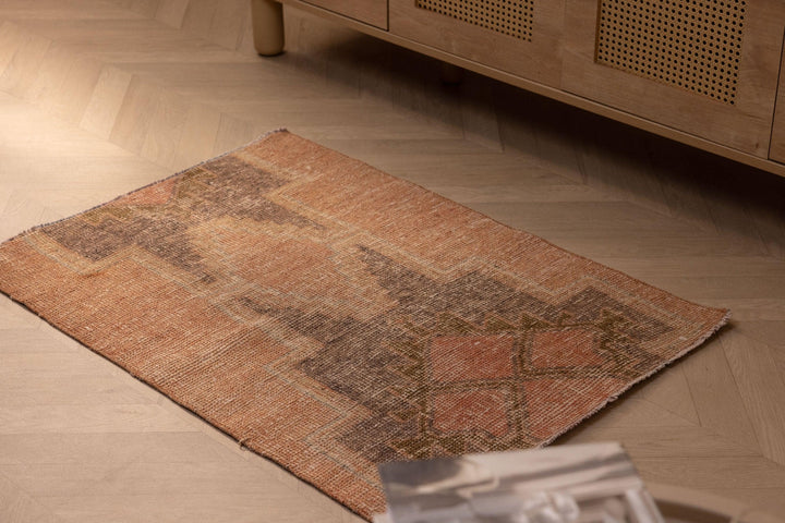 Hand-woven vintage Turkish doormat in brown and gray wool-cotton blend with geometric patterns on a wooden floor.