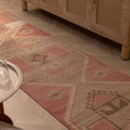 Hand-woven 2x11 ft vintage Turkish runner in faded pink and gray with geometric patterns, made from wool and cotton.