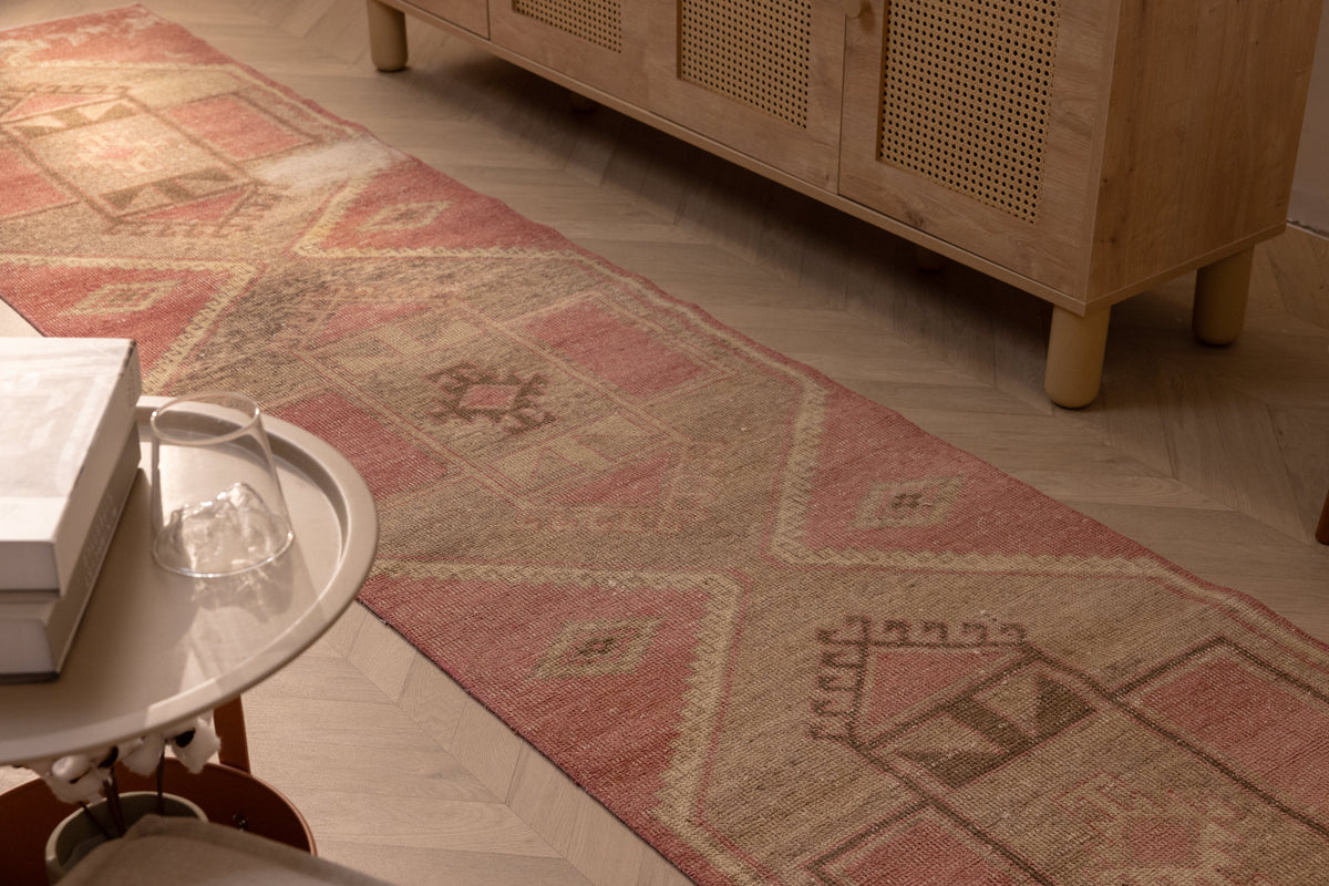 Hand-woven 2x11 ft vintage Turkish runner in faded pink and gray with geometric patterns, made from wool and cotton.