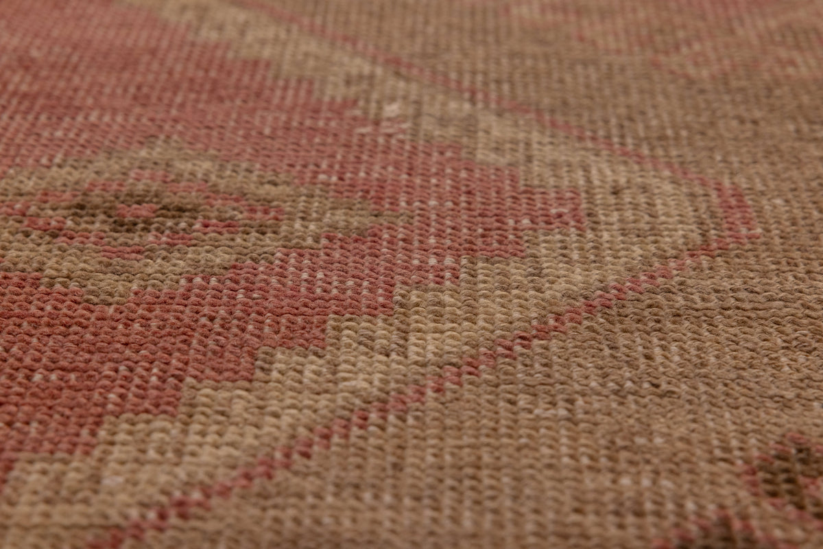 Close-up of a vintage Turkish runner rug with pink and gray geometric patterns in hand-woven wool and cotton.