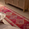 Handmade 2.5x12.6 ft wool and cotton runner rug in pink and beige with floral Persian-style patterns.