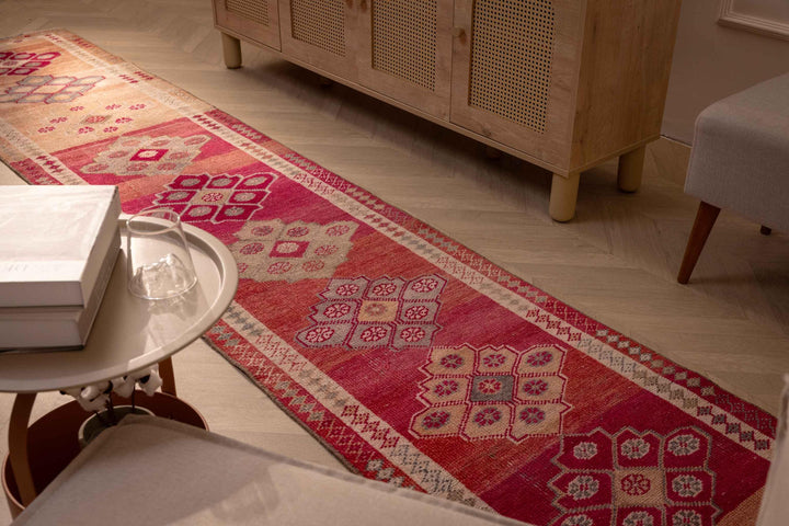 Handmade 2.5x12.6 ft wool and cotton runner rug in pink and beige with floral Persian-style patterns.
