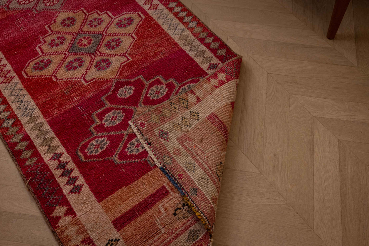 Handmade 2.5 x 12.6 ft wool and cotton runner rug in pink and beige with a bohemian floral Persian-style pattern.