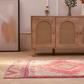 Handmade pink and white Persian-style wool-cotton runner rug with geometric patterns on a herringbone floor.
