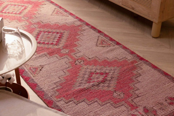 Handmade pink and white Persian-style wool and cotton runner rug with geometric bohemian patterns.