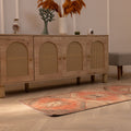 Hand-woven vintage Turkish runner rug in orange and brown geometric wool and cotton, displayed on a light wood floor.