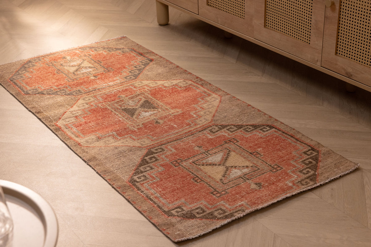 Vintage handmade Turkish runner rug in orange and brown with geometric patterns, crafted from wool and cotton.