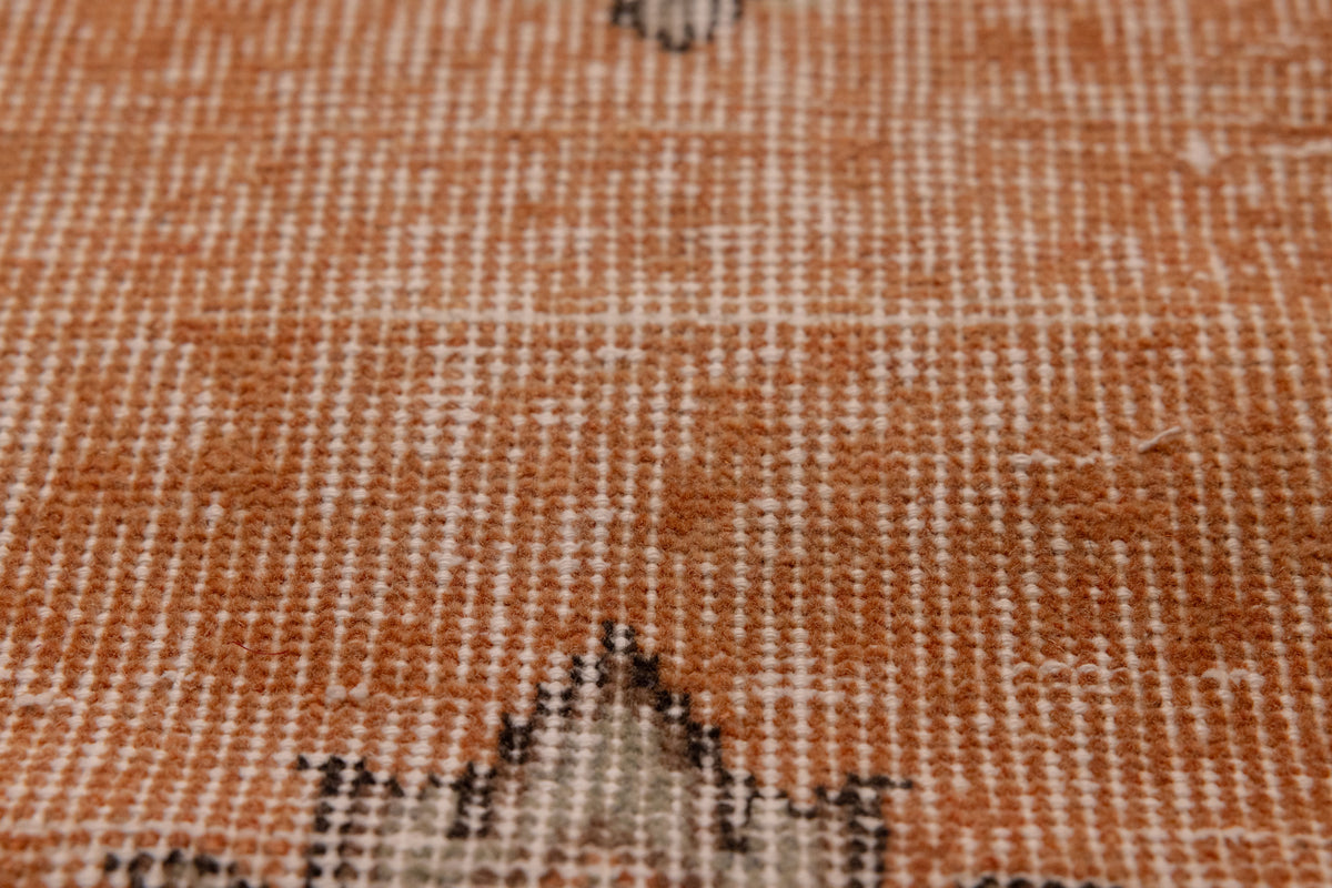 Close-up of a vintage hand-woven Isparta runner rug featuring burnt-orange wool and cotton with soft floral motifs.