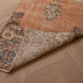 Vintage Isparta wool and cotton runner rug in burnt orange with blue floral patterns on a herringbone wood floor.
