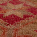 Close-up of a handmade wool and cotton runner rug featuring a brown and pink floral, maximalist Persian-style pattern.