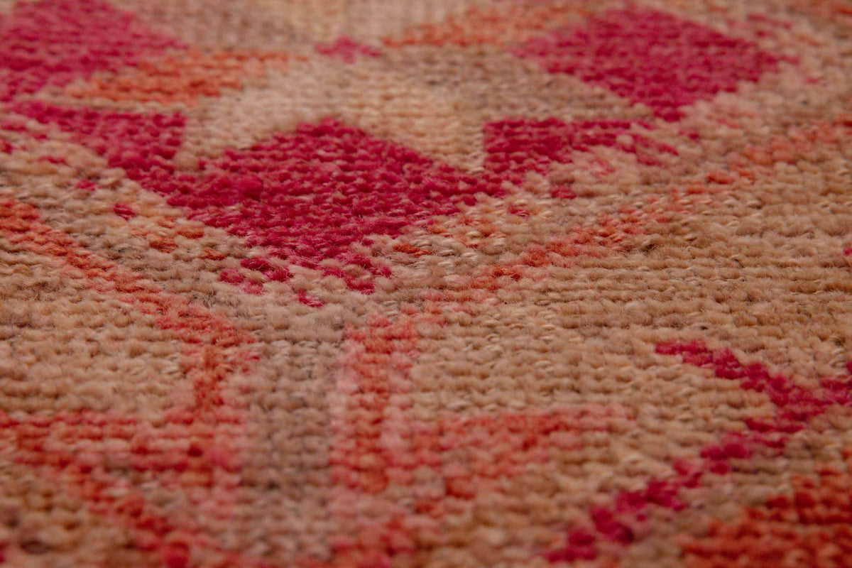 Close-up of a handmade wool and cotton Persian-style runner rug featuring a bohemian floral pattern in pink and brown.