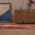 Handmade 3.4x13 ft Persian-style runner rug in orange and navy with a floral pattern, crafted from wool and cotton.