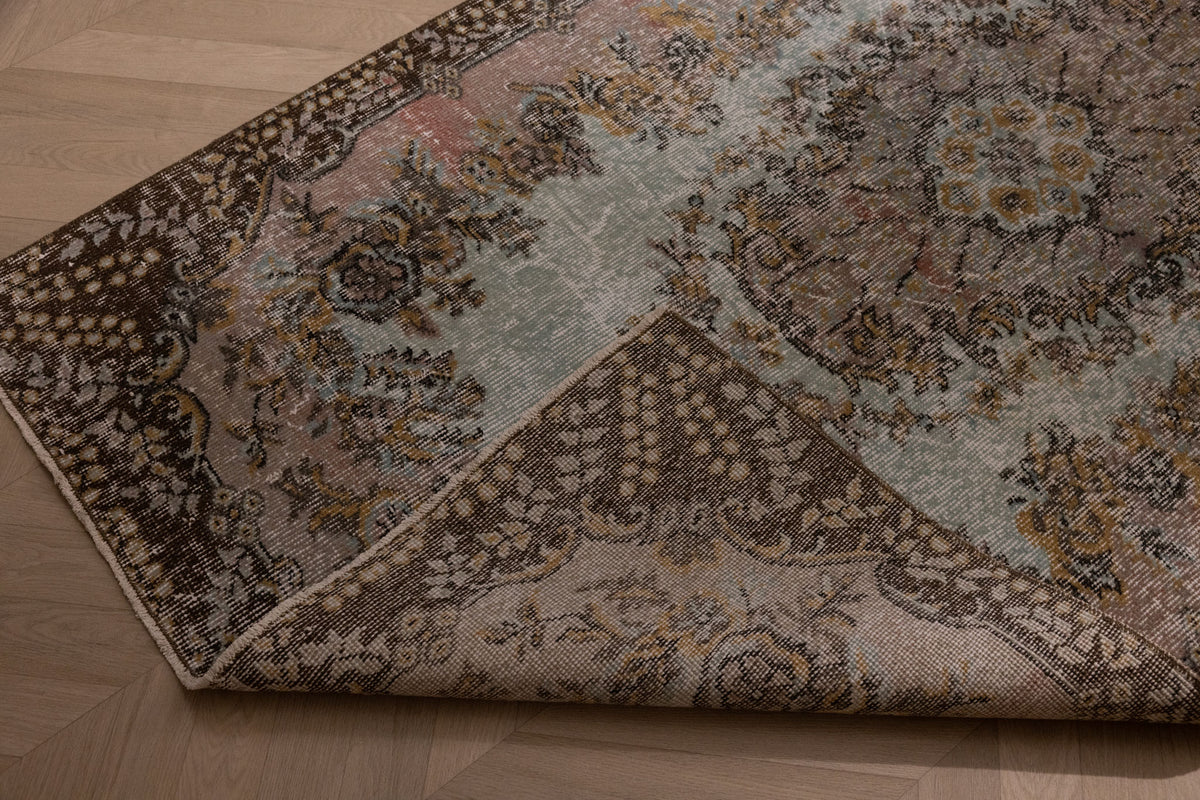 Hand-woven vintage Isparta wool and cotton rug in brown and gray with maximalist floral patterns on a wooden floor.