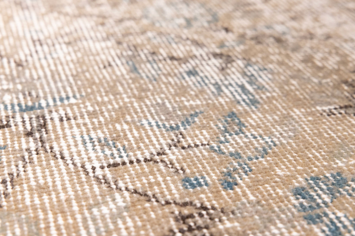 Close-up of a vintage hand-woven Isparta rug featuring orange and blue floral patterns on a wool and cotton blend.