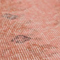 Close-up of a vintage pink overdyed Turkish Isparta wool and cotton rug with faded floral patterns.