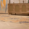 Vintage 4x7 ft hand-woven Turkish rug in orange and beige with a floral medallion pattern on a light wood floor.