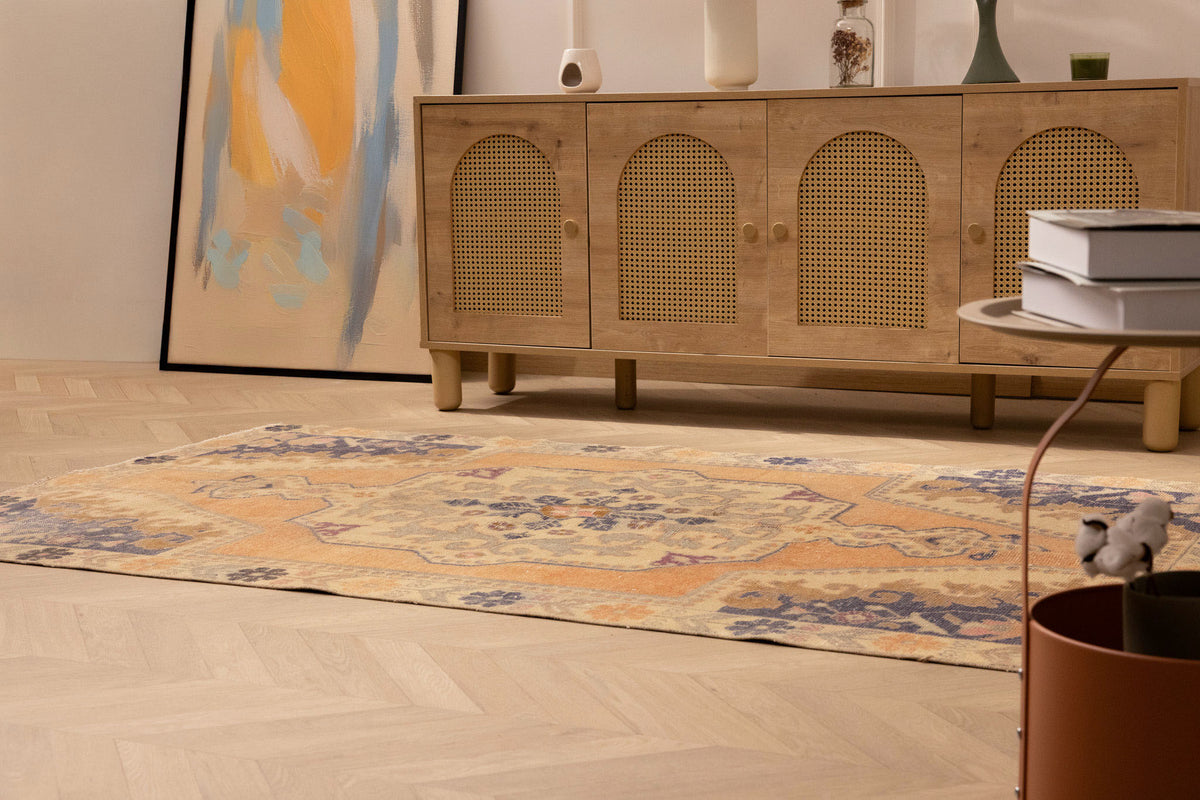 Vintage 4x7 ft hand-woven Turkish rug in orange and beige with a floral medallion pattern on a light wood floor.