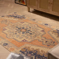 Hand-woven 4x7 ft vintage Turkish rug in orange and beige with a traditional floral medallion design.