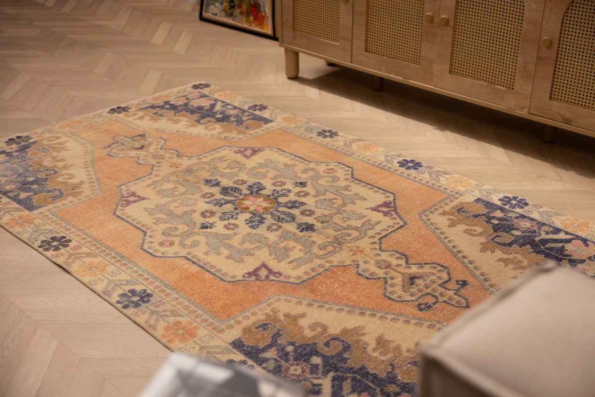 Hand-woven 4x7 ft vintage Turkish rug in orange and beige with a traditional floral medallion design.