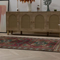 Hand-woven 4x6 ft vintage Kars wool rug in red and brown with intricate geometric patterns in a bohemian living room.