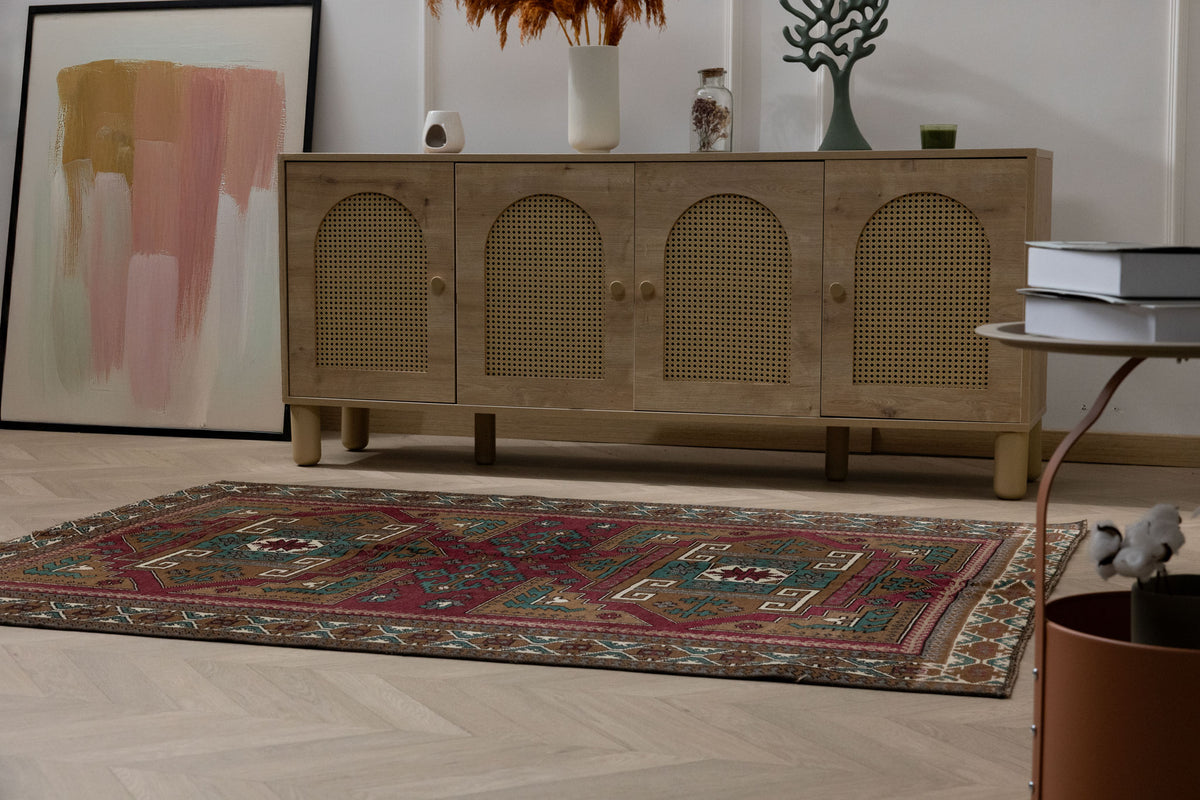 Hand-woven 4x6 ft vintage Kars wool rug in red and brown with intricate geometric patterns in a bohemian living room.