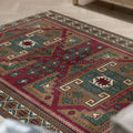 Hand-woven 4x6 ft vintage Kars wool rug featuring geometric patterns in red, brown, and teal on a herringbone floor.