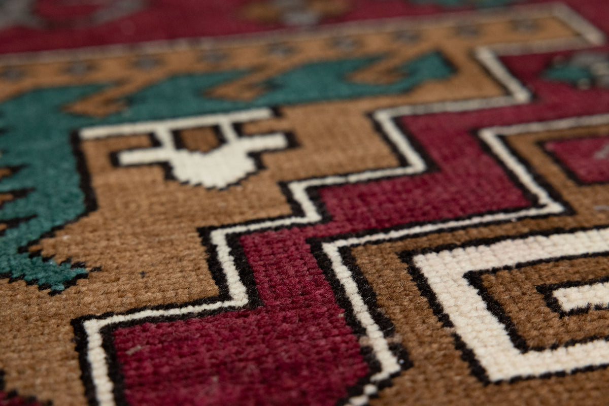 Hand-woven vintage Kars wool rug with red, brown, and teal geometric patterns in a low-pile bohemian style.