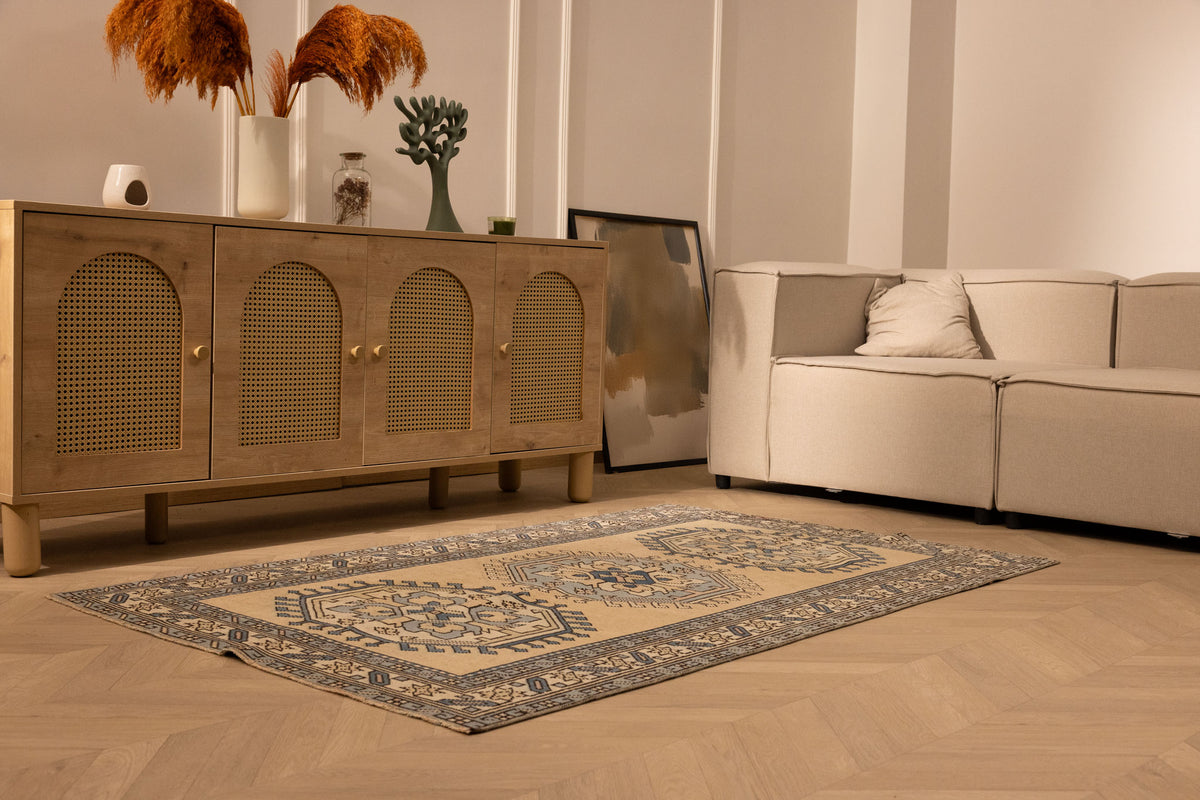 Hand-woven 3x6 ft vintage Oushak wool rug in beige and navy with geometric patterns in a modern bohemian living room.